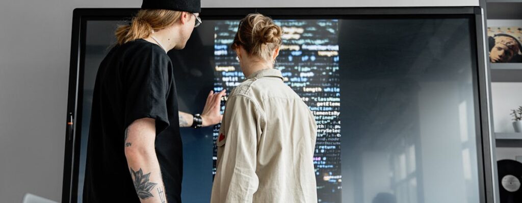 Two professionals collaborating on software development in a modern indoor setting.